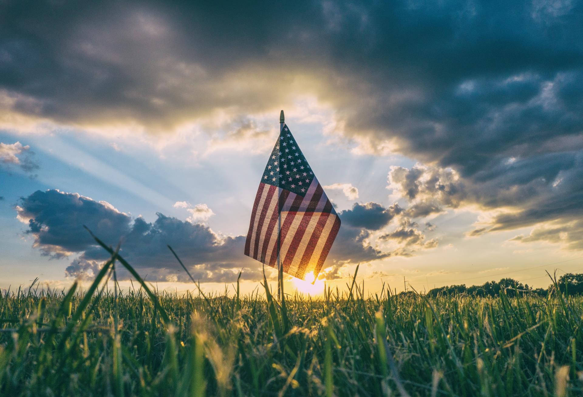 Solitary flag stands in grass in front of a sunrise