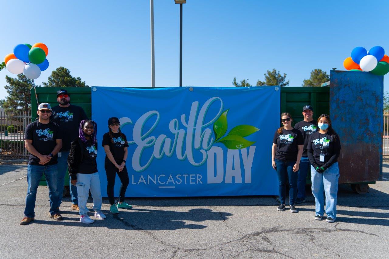 Environmental Team poses in front of a dumpster that says 