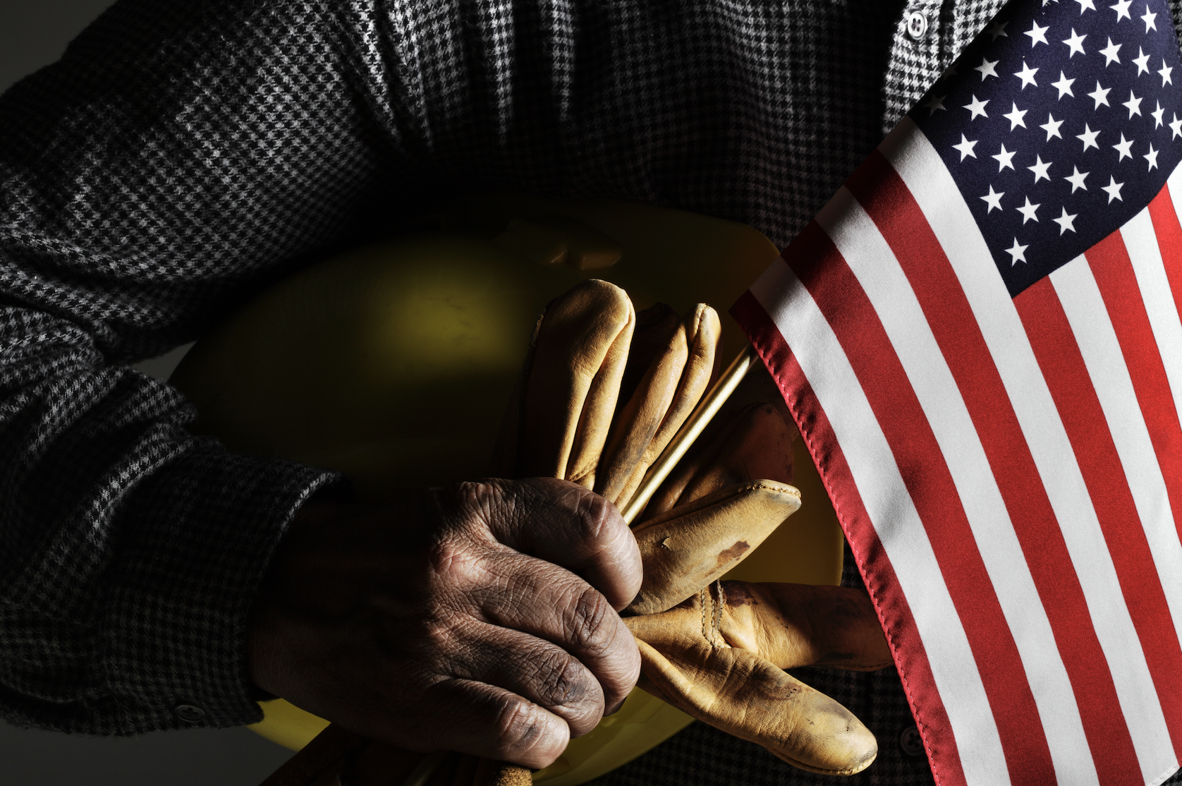 Laborer holds american flag and work gloves