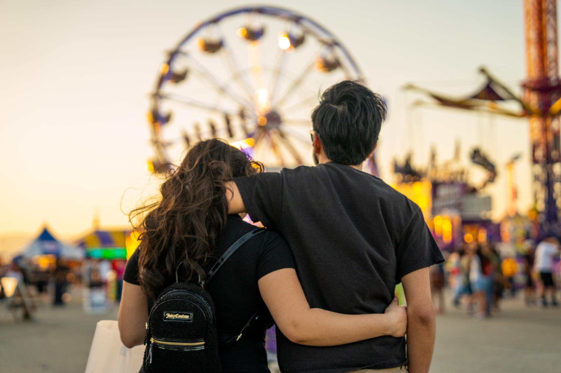 a couple gaze at the poppy festival ferris wheel with arms around each other